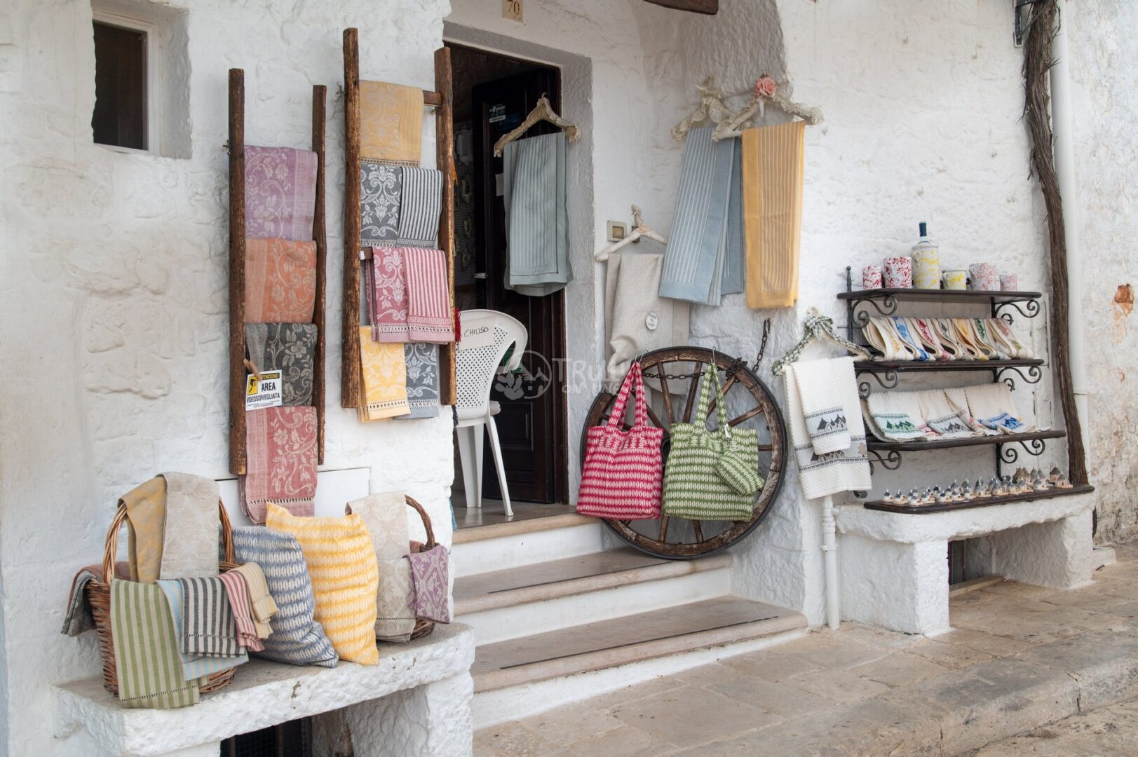 guida-alberobello-trullionline-06 Tessuti artigianali esposti davanti a una bottega