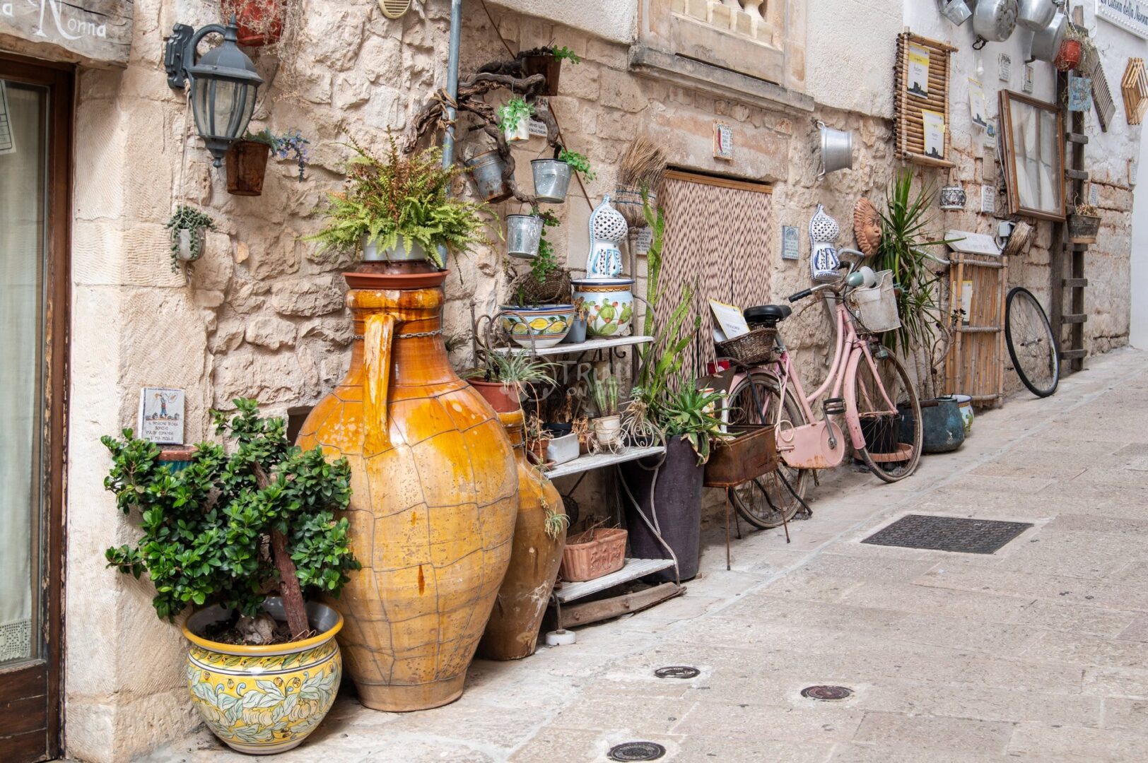 guida-ceglie-messapica-trullionline-10 Angolo di vicolo con grandi anfore gialle, biciclette d'epoca, piante e oggetti appesi al muro