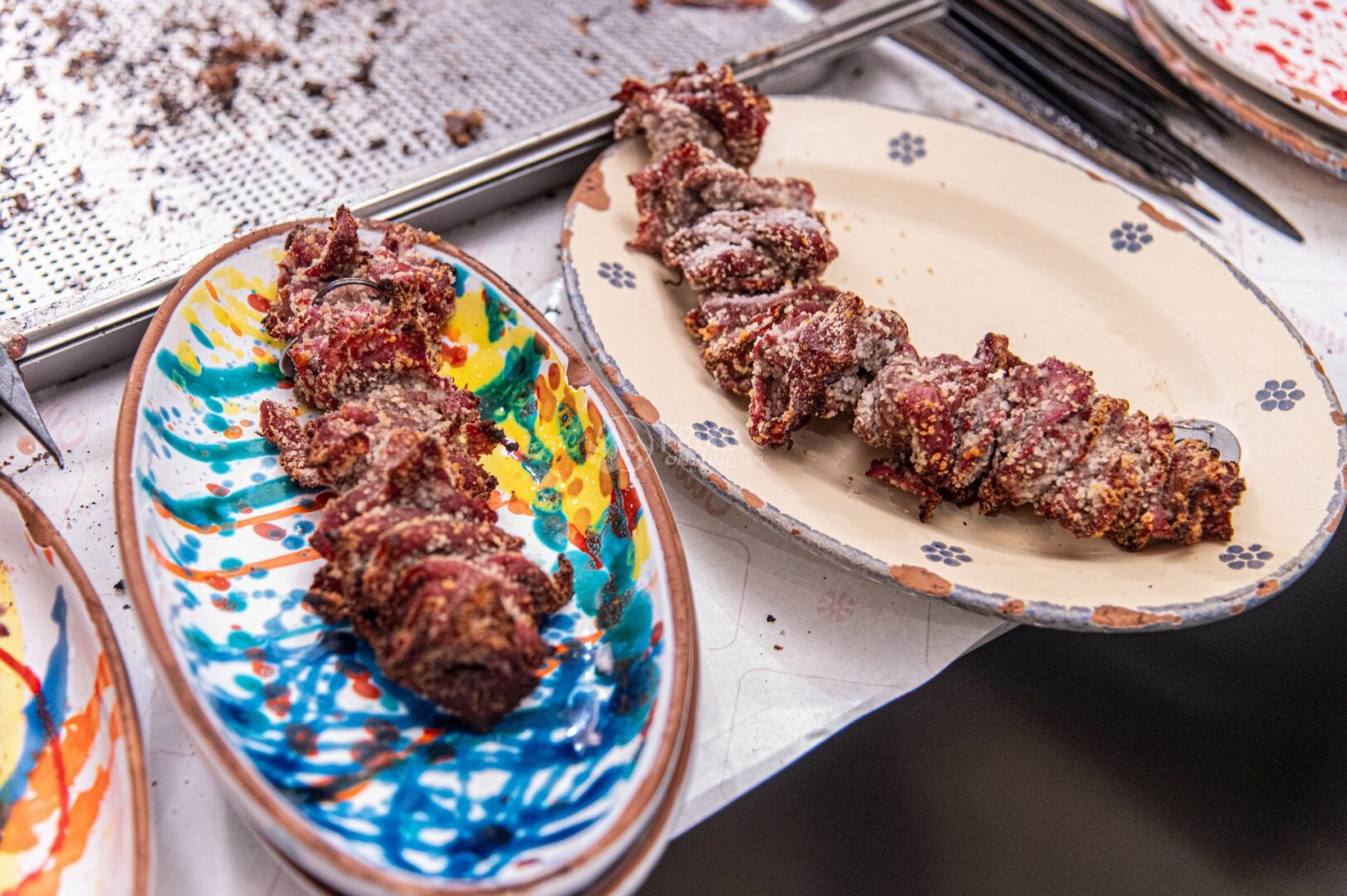 guida-cisternino-trullionline-13 Due piatti decorati con involtini e spiedini di carne appena grigliati, con la griglia sullo sfondo