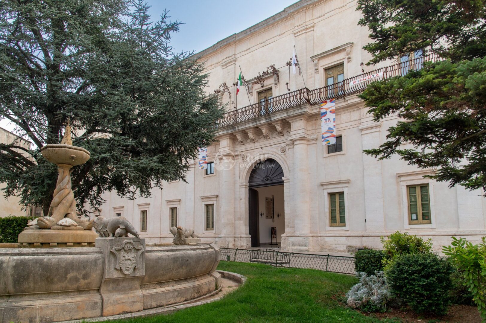 guida-martina-trullionline-12 Fontana in pietra con sculture davanti a un palazzo storico, tra cedri e prato, a Martina Franca