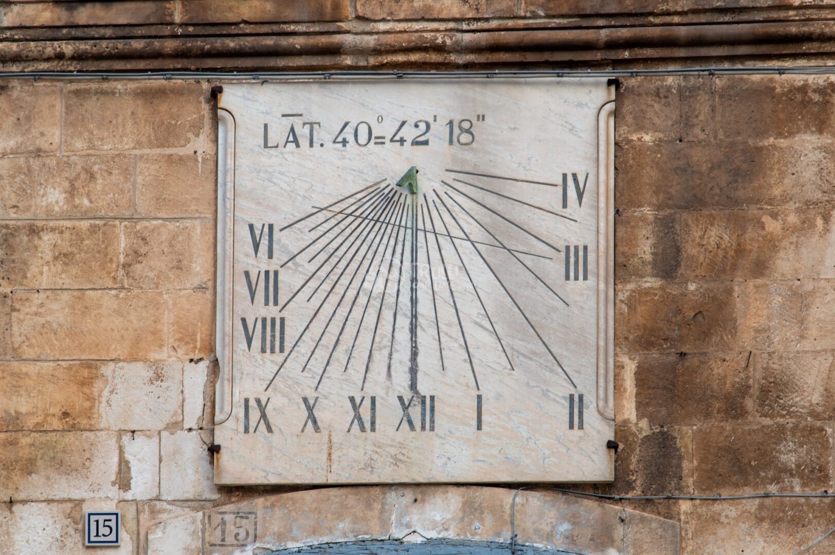 guida-martina-trullionline-17 Meridiana in marmo con numeri romani e la scritta Lat. 40° 42' 18'' su un muro di pietra a Martina Franca