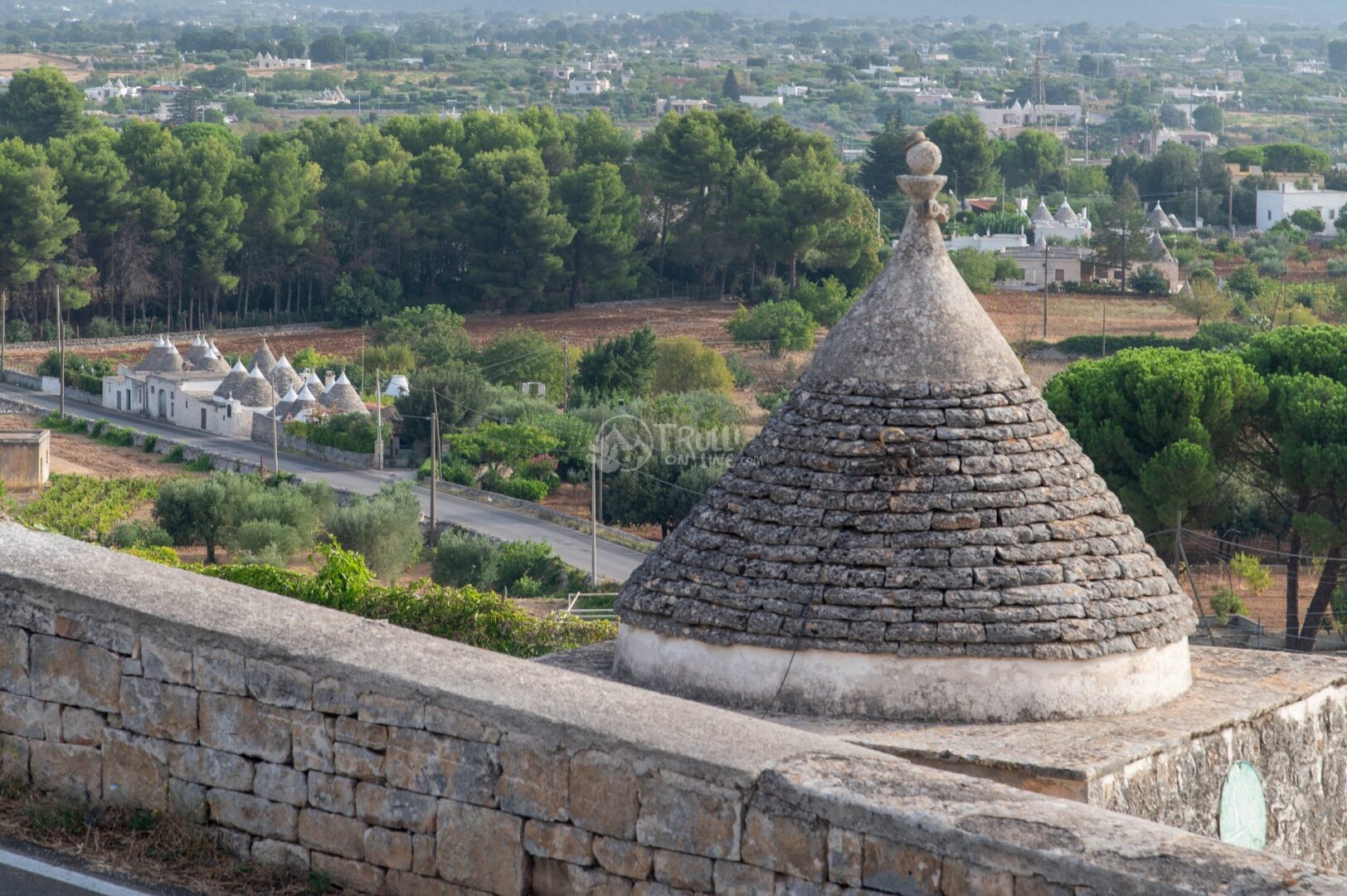 guida-ostuni-trullionline-04 Cono di un trullo in primo piano con altri trulli e la campagna della Valle d'Itria sullo sfondo